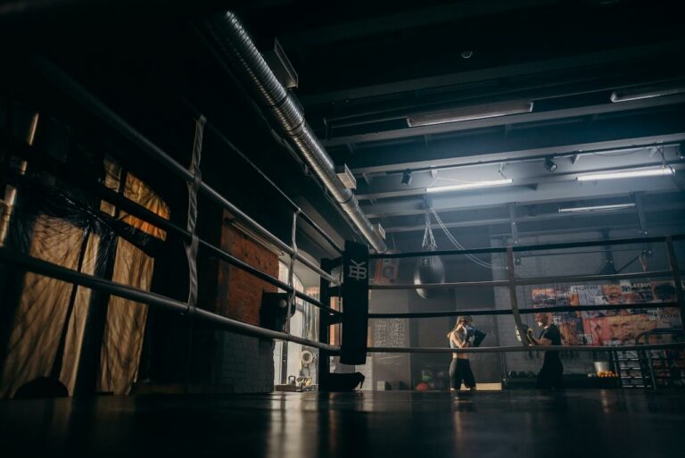 A boxing gym while trainer and trainee training in the background.